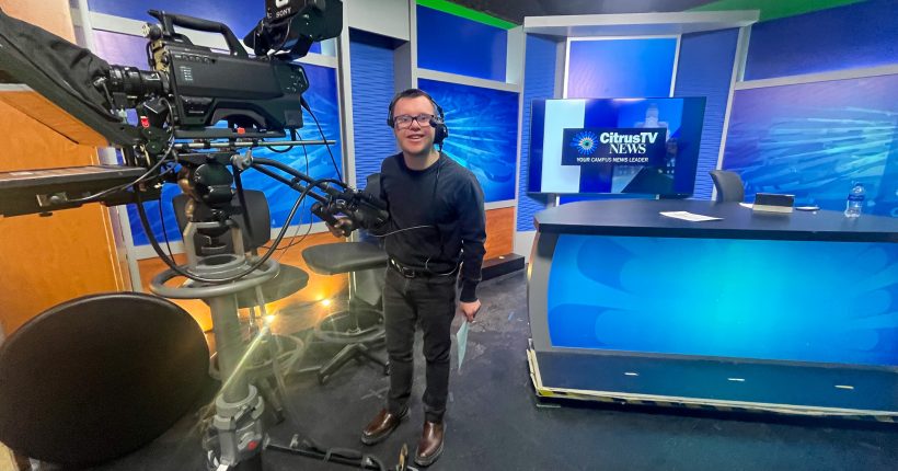 InclusiveU Student, Matthew Falanga, behind a camera with headphones on in a news studio.